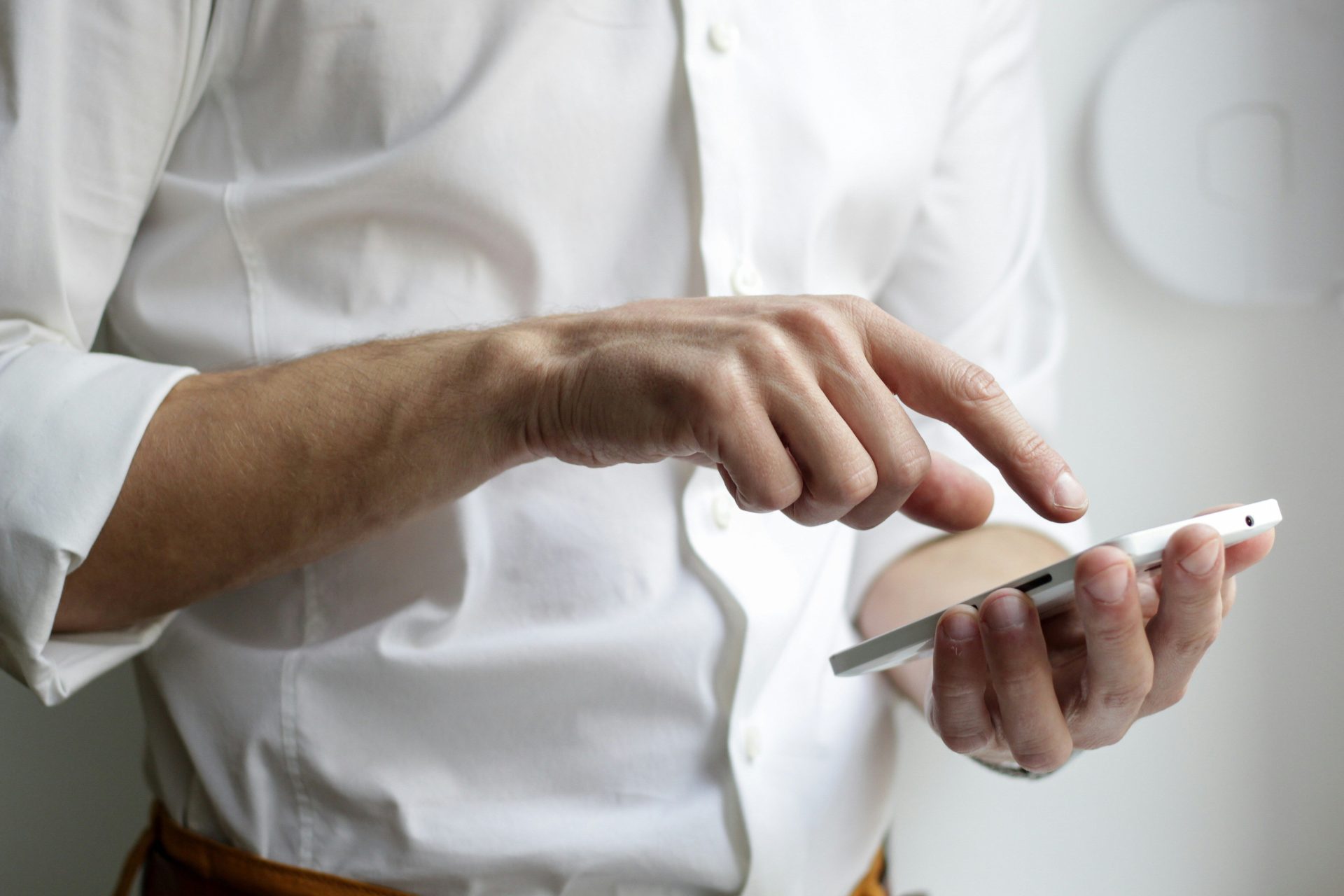 Person in weißem Hemd hält ein weißes Android-Smartphone.